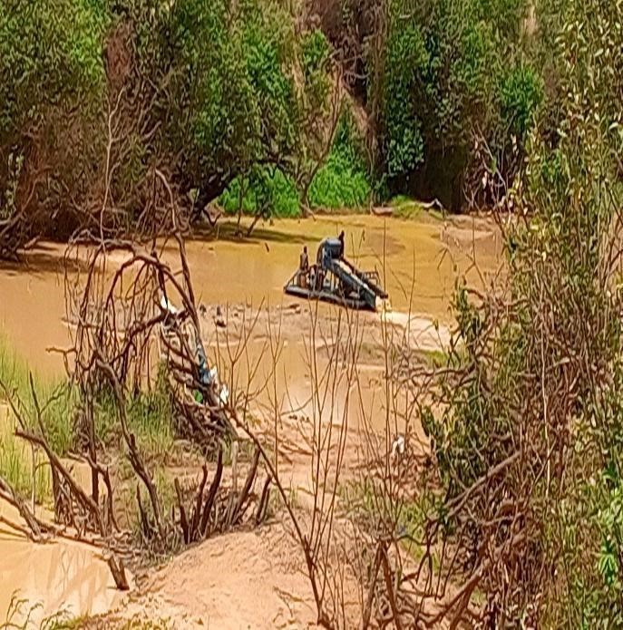 L'image montre un équipement flottant (une drague) utilisé pour aspirer le sable et le gravier du lit de la rivière. Cette méthode trouble l'eau, contamine les écosystèmes aquatiques (souvent avec du mercure ou du cyanure) et menace les réserves d'eau potable / Ph:SD