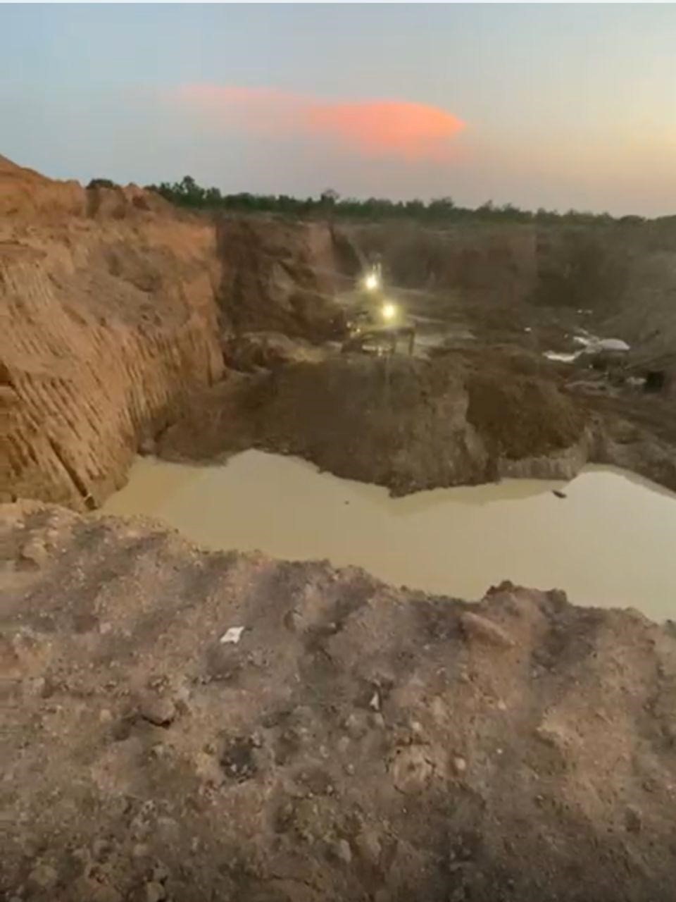 Vue nocturne d'une vaste carrière d'orpaillage clandestine. Les lumières des engins lourds (visible au centre) et la hauteur des murs d'excavation mettent en évidence l'ampleur de la destruction environnementale / Ph:SD